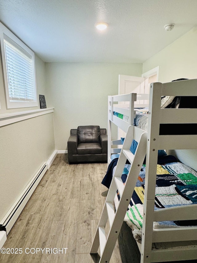 5670 W Calico Dr, Wasilla, AK 99654 - bedroom featuring a baseboard heating unit, wood finished floors, baseboards, and a textured ceiling