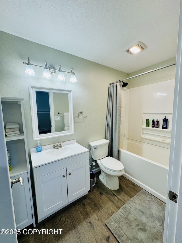 5670 W Calico Dr, Wasilla, AK 99654 - full bath featuring wood finished floors, vanity, toilet, a textured ceiling, and shower / bath combo with shower curtain
