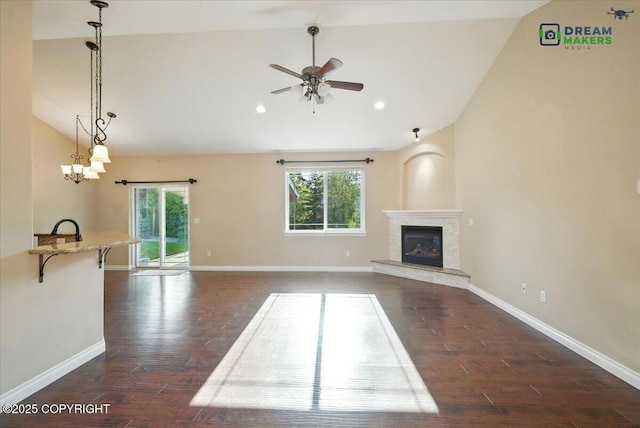 7782 W Arlie Rd, Wasilla, AK 99623 - unfurnished living room with vaulted ceiling, plenty of natural light, a ceiling fan, dark wood-type flooring, and a glass covered fireplace