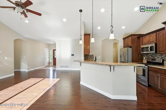 7782 W Arlie Rd, Wasilla, AK 99623 - kitchen with stainless steel appliances, arched walkways, a breakfast bar, a ceiling fan, and decorative backsplash