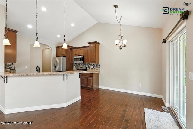 7782 W Arlie Rd, Wasilla, AK 99623 - kitchen with appliances with stainless steel finishes, a kitchen breakfast bar, a chandelier, backsplash, and vaulted ceiling