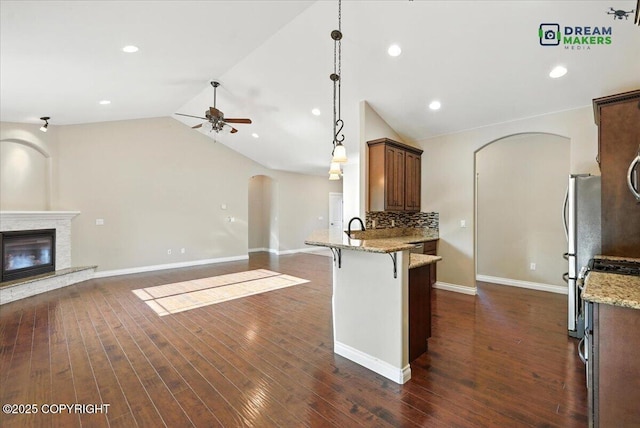 7782 W Arlie Rd, Wasilla, AK 99623 - kitchen with arched walkways, ceiling fan, a peninsula, a breakfast bar area, and freestanding refrigerator