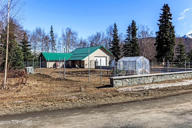 view of front facade featuring fence, an outdoor structure, metal roof, an exterior structure, and a garage