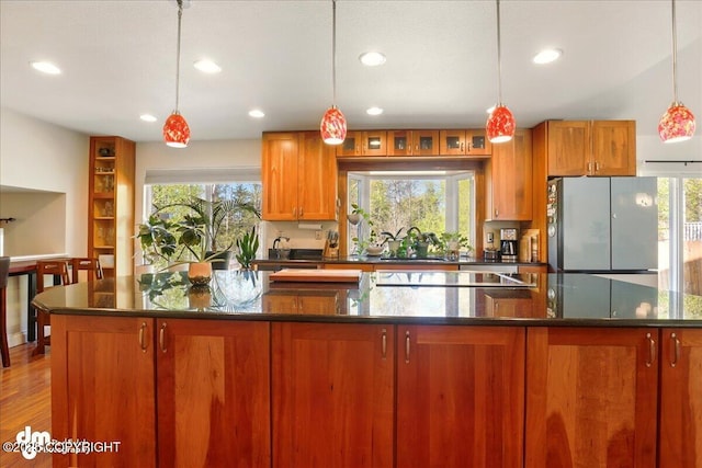 kitchen featuring freestanding refrigerator, black electric stovetop, a sink, recessed lighting, and a spacious island