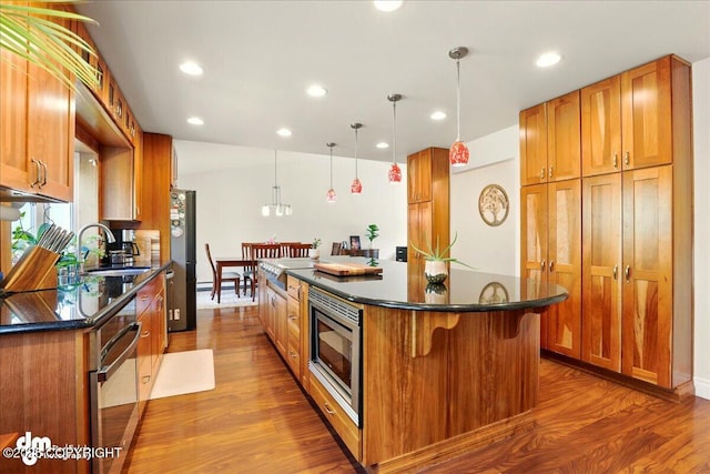 kitchen featuring appliances with stainless steel finishes, dark countertops, dark wood-type flooring, and recessed lighting