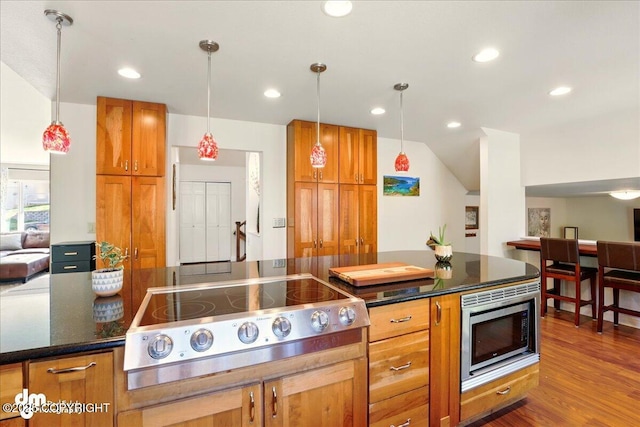 kitchen featuring cooktop, stainless steel microwave, brown cabinets, pendant lighting, and recessed lighting