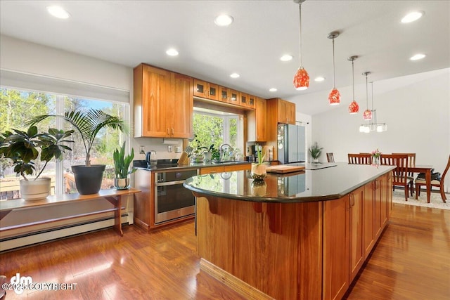 kitchen featuring stainless steel appliances, a sink, recessed lighting, a center island, and wood finished floors