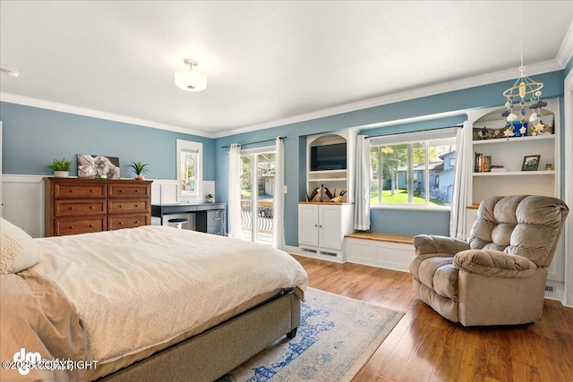 bedroom featuring access to outside, ornamental molding, multiple windows, and wood finished floors