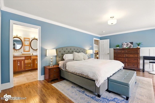 bedroom with crown molding, light wood-type flooring, and ensuite bathroom
