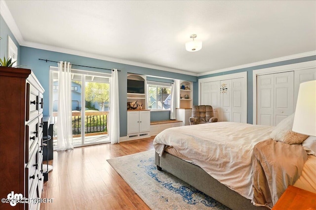 bedroom featuring access to exterior, two closets, wood finished floors, and ornamental molding