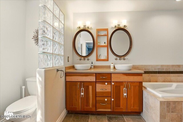 full bath featuring double vanity, toilet, and tiled bath