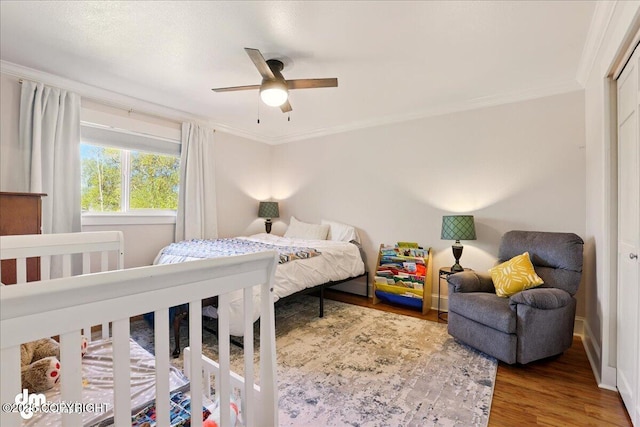 bedroom with wood finished floors, crown molding, and ceiling fan