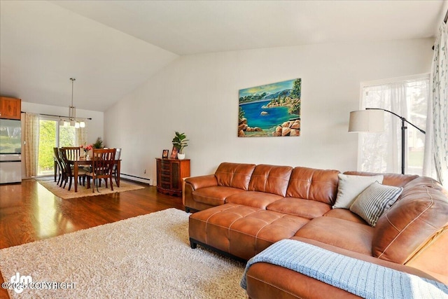 living room featuring wood finished floors, a baseboard heating unit, vaulted ceiling, and a chandelier