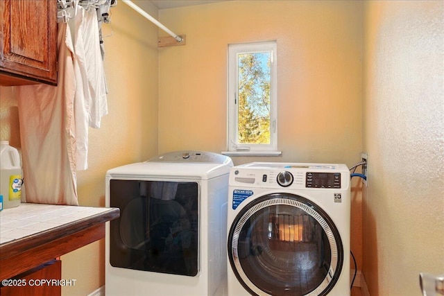 washroom featuring washing machine and clothes dryer and cabinet space