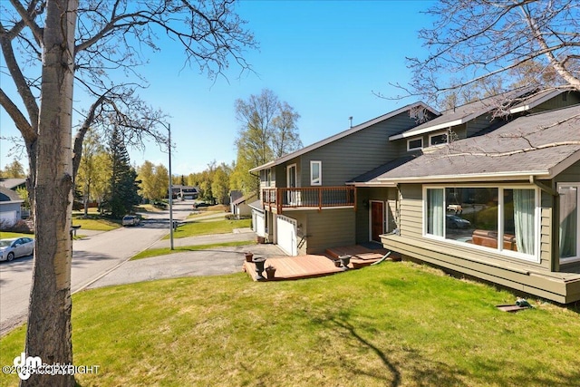 view of property exterior featuring a deck, a lawn, asphalt driveway, and an attached garage