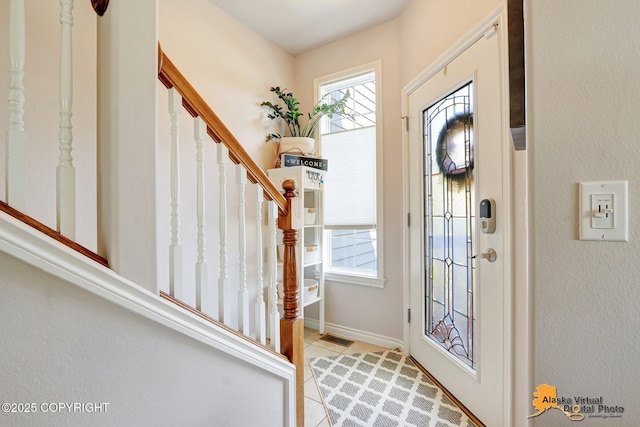 entryway with stairway, baseboards, and light tile patterned floors