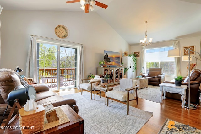 living area with a chandelier, high vaulted ceiling, a ceiling fan, and wood finished floors