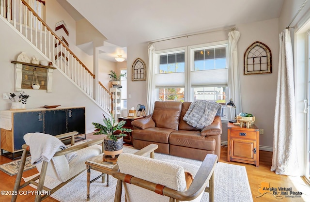 living area featuring stairs, light wood-style flooring, and baseboards