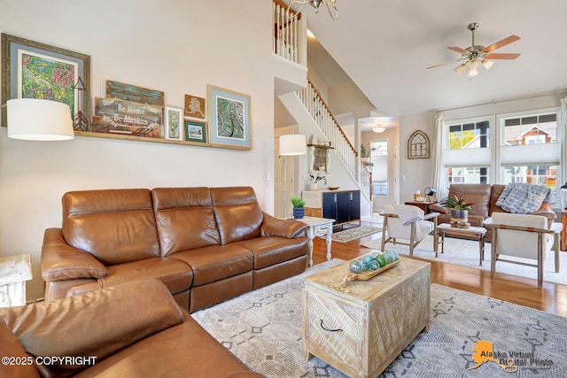 living room featuring stairway, a ceiling fan, wood finished floors, and high vaulted ceiling
