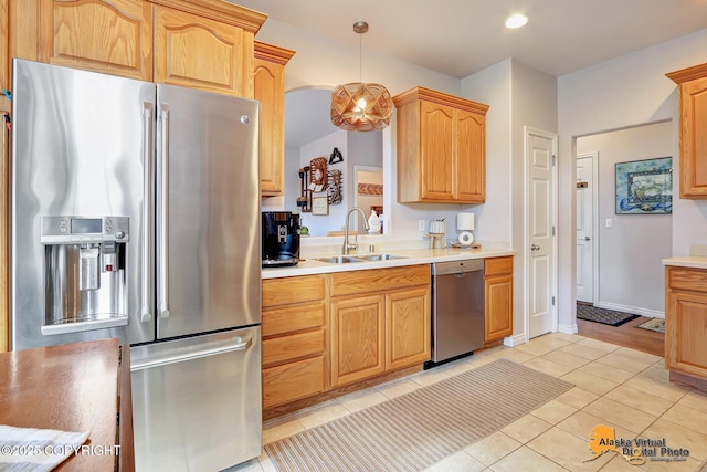 kitchen featuring appliances with stainless steel finishes, a sink, light tile patterned floors, light countertops, and pendant lighting