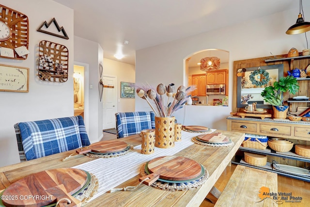 dining space with arched walkways and wood finished floors