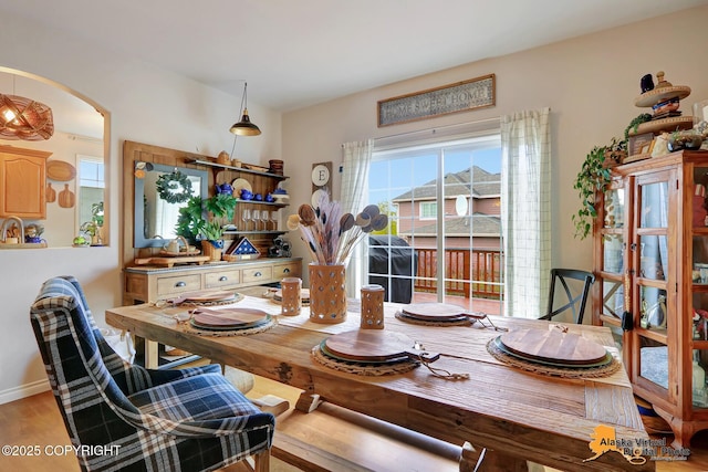 dining area featuring arched walkways and wood finished floors