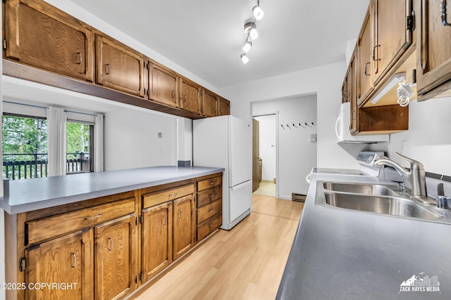 400 W 76th Ave # 204, Anchorage, AK 99518 - kitchen with white appliances, a peninsula, light wood-type flooring, brown cabinets, and a sink