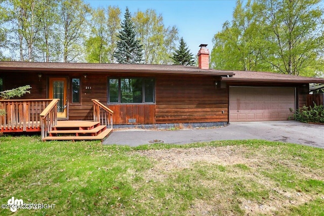 view of front of house with a chimney, a garage, asphalt driveway, a front yard, and a wooden deck