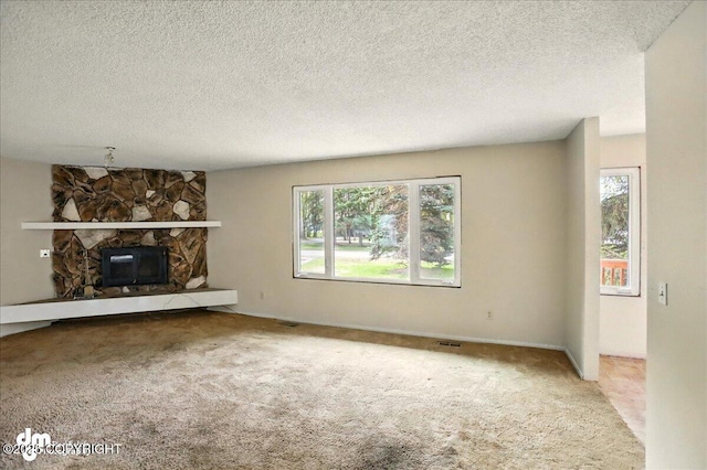 unfurnished living room with carpet, a fireplace, and a textured ceiling