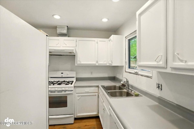 kitchen with white gas stove, under cabinet range hood, white cabinets, a sink, and light countertops