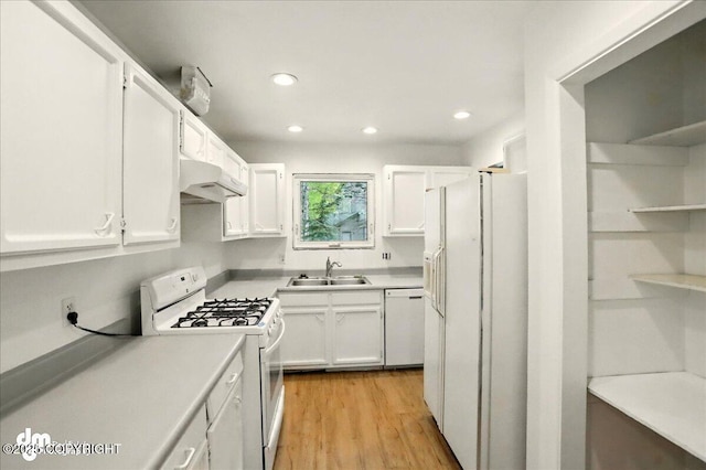 kitchen featuring white appliances, under cabinet range hood, white cabinetry, a sink, and recessed lighting