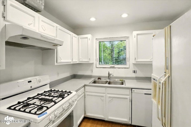 kitchen featuring white appliances, under cabinet range hood, a sink, white cabinets, and light countertops