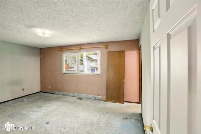 empty room featuring carpet floors, a textured ceiling, and baseboards