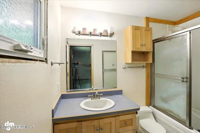 bathroom with vanity, toilet, and combined bath / shower with glass door