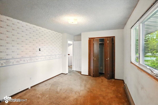 unfurnished bedroom with carpet flooring, baseboards, a closet, a textured ceiling, and baseboard heating