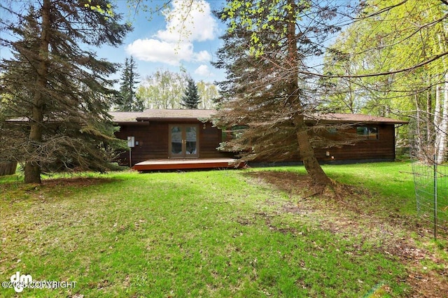 rear view of house with a deck, a yard, and french doors