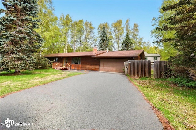 ranch-style house with an attached garage, a chimney, and driveway
