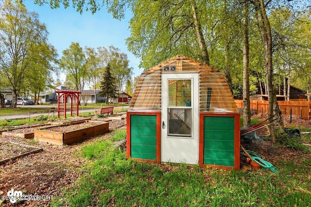 view of greenhouse featuring a vegetable garden and fence