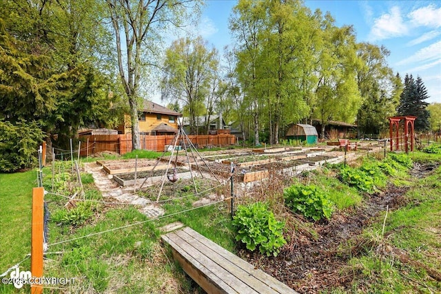 view of yard with a vegetable garden, fence, a shed, and an outbuilding