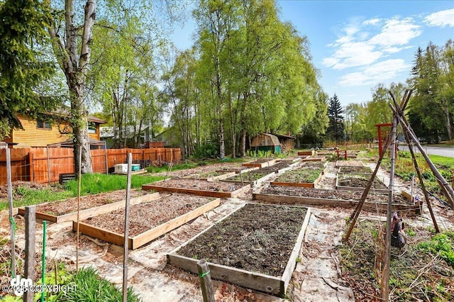 view of yard with a vegetable garden, fence, a storage unit, and an outbuilding