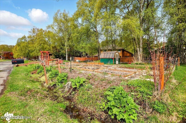view of yard featuring a vegetable garden, fence, and an outdoor structure