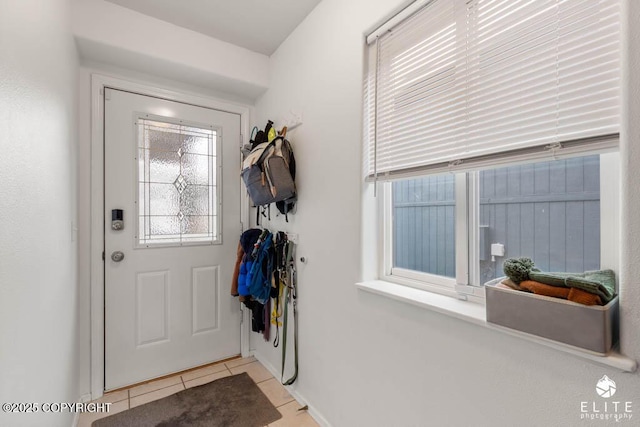 doorway to outside featuring tile patterned flooring and baseboards