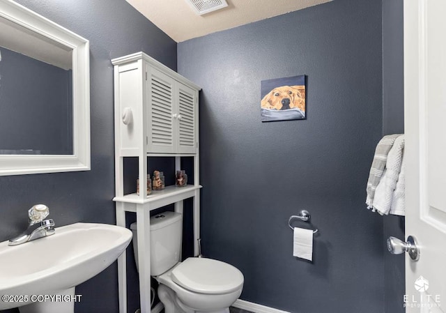 half bathroom featuring a sink, toilet, and baseboards