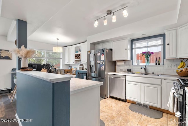 kitchen featuring stainless steel appliances, a sink, light countertops, white cabinetry, and backsplash