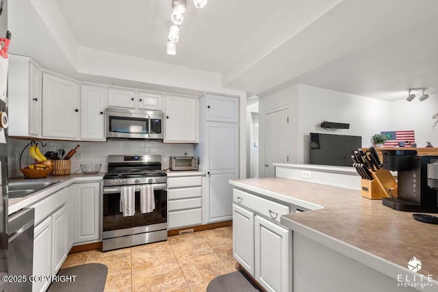 kitchen featuring appliances with stainless steel finishes, decorative backsplash, white cabinets, and light countertops