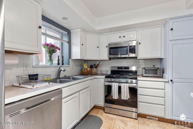 kitchen featuring stainless steel appliances, a sink, light countertops, white cabinetry, and tasteful backsplash
