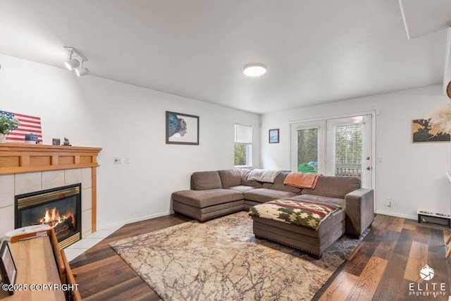 living room with a tile fireplace, wood finished floors, and baseboards