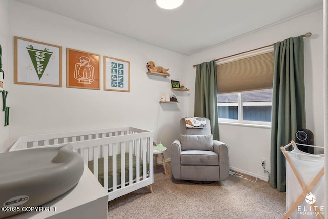 carpeted bedroom with a crib and baseboards