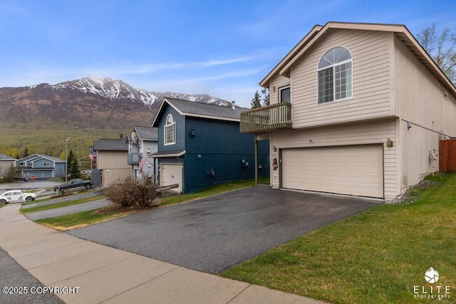 view of front of home with a garage, a mountain view, driveway, and a front lawn