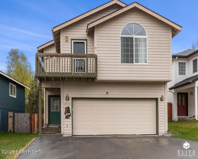 view of front facade featuring a balcony, driveway, a garage, and fence